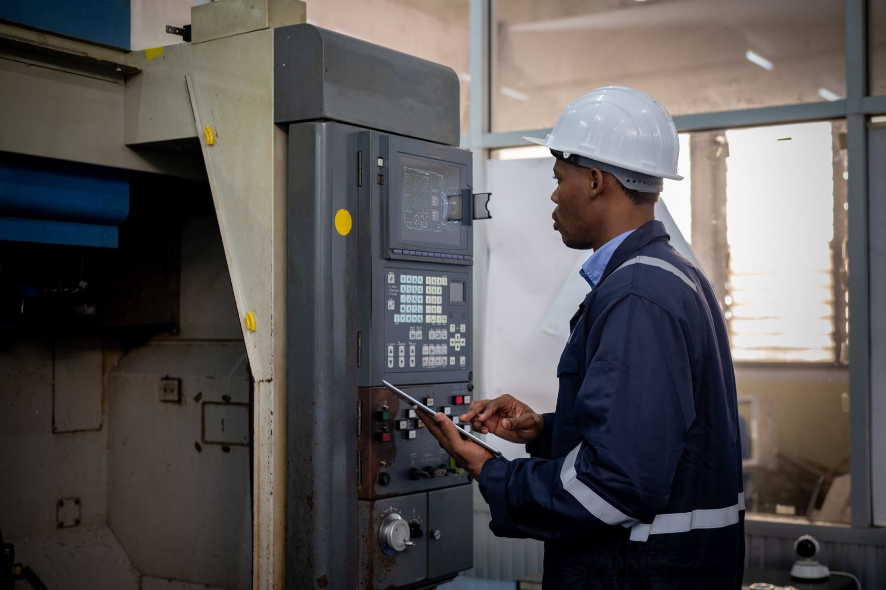 Engineer checking a machine control panel with a tablet